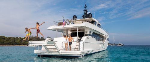 Two boys jumping from the swim platform of a boat during family yacht charter vacations