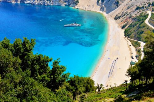 The white sandy beach of Myrtos on the island of Kefalonia in Greece, with a luxurious superyacht at anchor