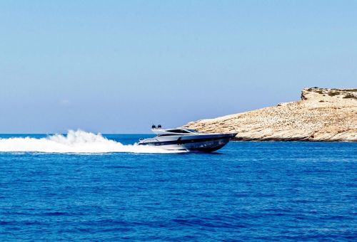 A sporty motor yacht cruising along the coast of Santorini