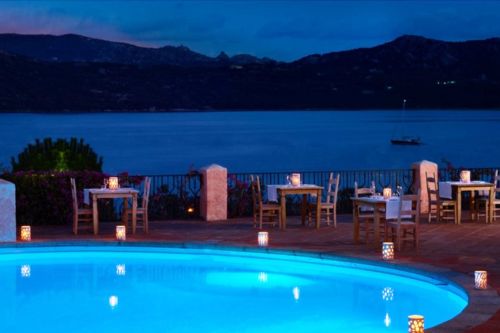 The pool of the Mira Luna restaurant with a view of the bay of Cannigione and some tables set up for dinner