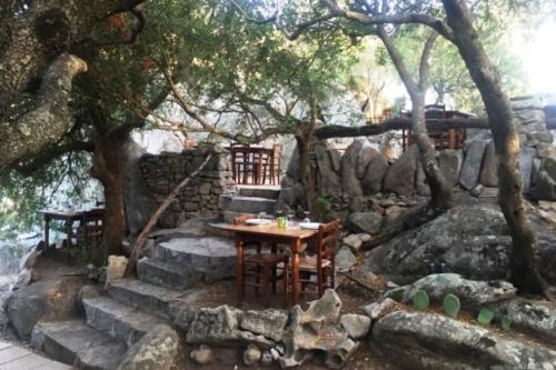 Tables set in a rocky garden at the traditional Pedristellas restaurant in Porto Rotondo