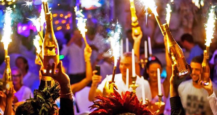 Champagne bottles with sparklers and people dancing during a party night at L'Opra in St Tropez