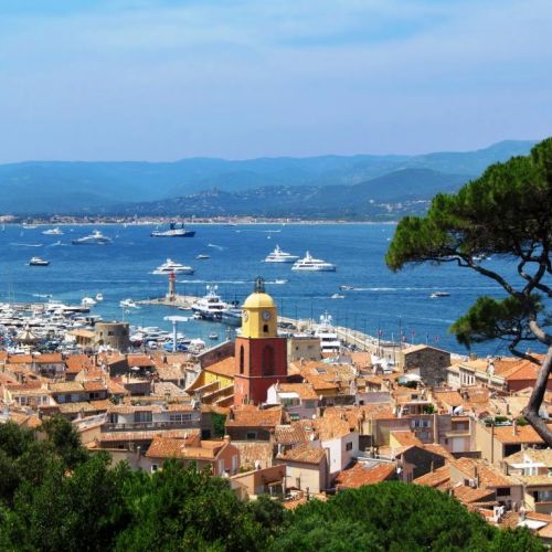 View of the village of St Tropez with its bell tower and charter yachts at anchor in the bay