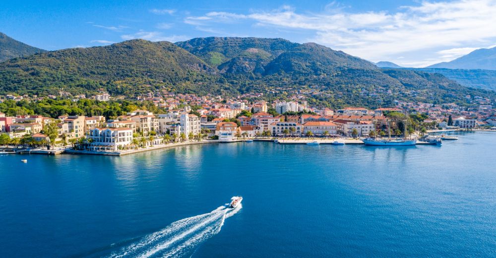 Aerial view of the town of Tivat in Montenegro with a yacht cruising in the bay
