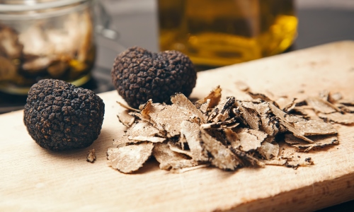 Two white truffles and shavings on an olive wood plank