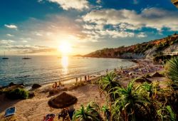 People relaxing and sunbathing on a white sandy beach in the Balearic islands