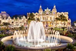 The casino of Monaco seen at night with its lights and a fountain on the square