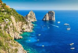 Aerial view of the Faraglioni rock formations off the island of Capri with a multitude of yachts at anchor