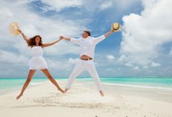 A happy honeymoon couple jumping on a beach