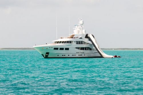 A luxury motor yacht at anchor with a waterslide from the top of the boat into the sea