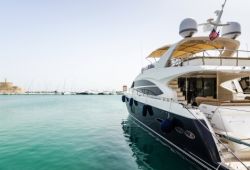 A luxury flybridge motor yacht moored in a Mediterranean port ready for charter