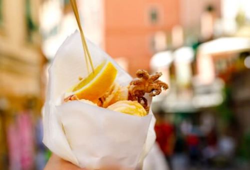 A woman holding a cone of fried seafood in the village of Riomaggiore