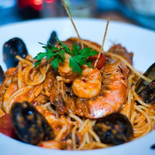 A plate of seafood pasta with mussels in a waterfront restaurant