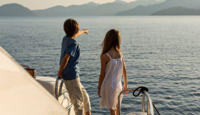 Kids looking at the sea from a charter yacht with their parents on the aft deck