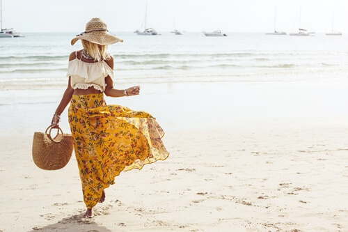 A woman in stylish clothes walking on the beach