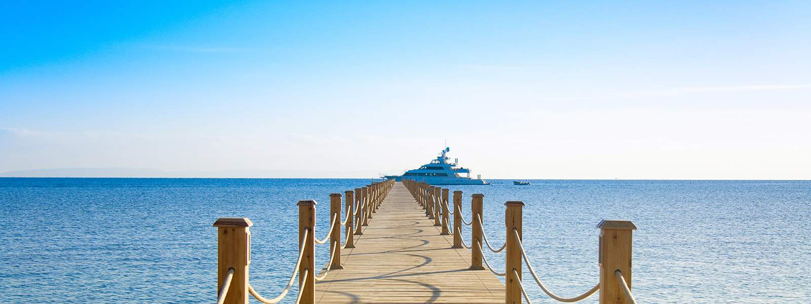 A wooden pontoon with a charter yacht ready to welcome charter guests