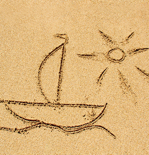 Hand drawing in the sand of a sailboat cruising on the water